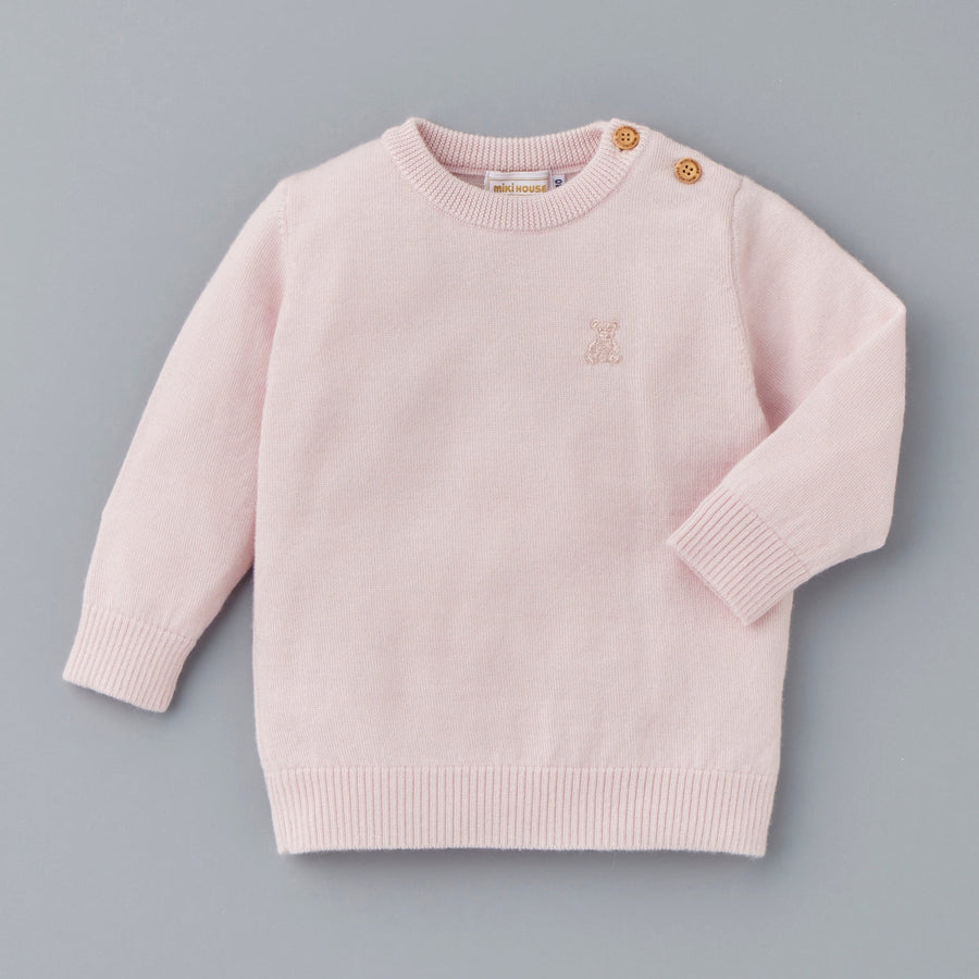 Pink cashmere sweater with two shoulder fastenings.
