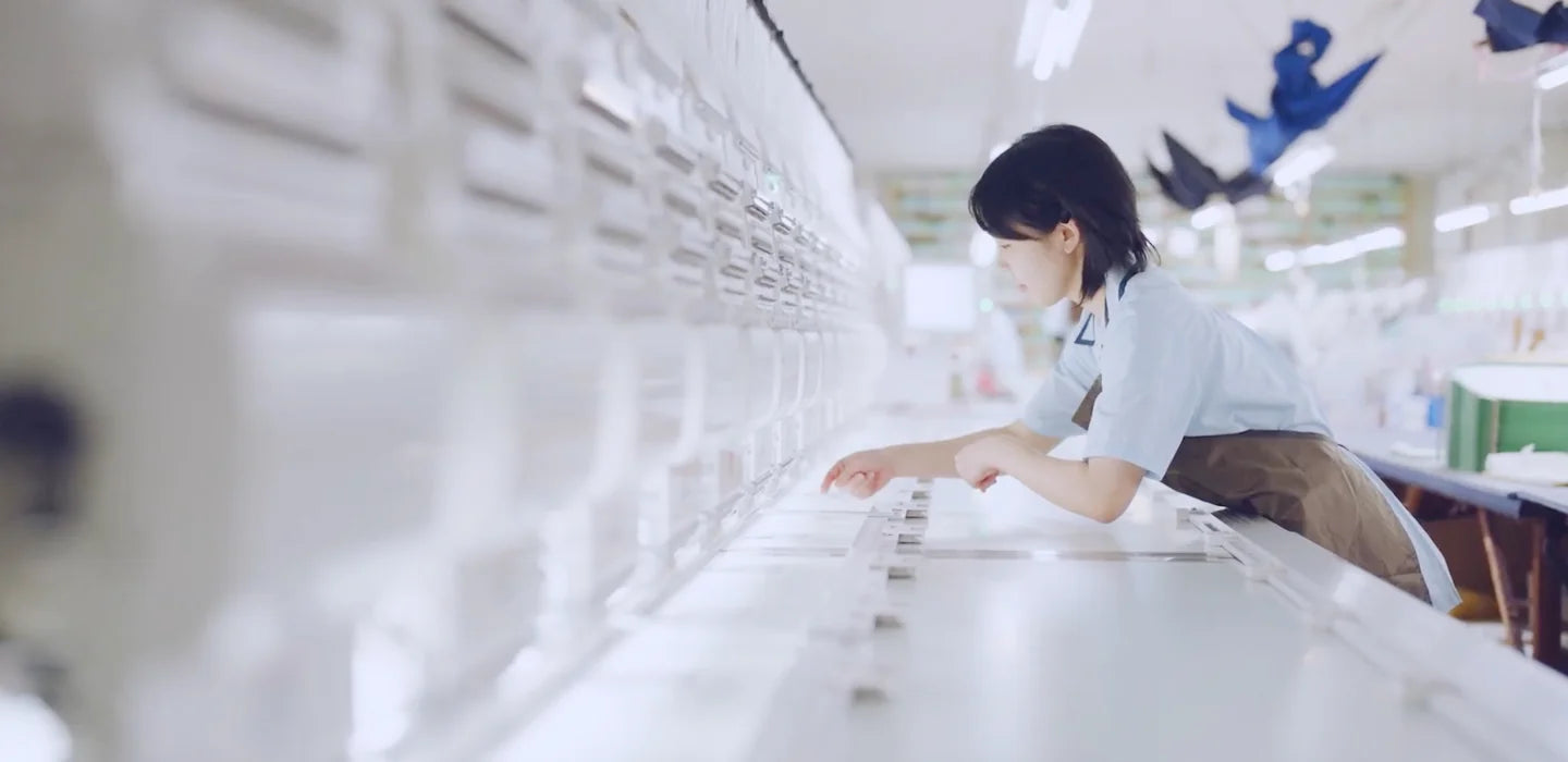 A craftsperson works on white fabric in a bright textile workshop