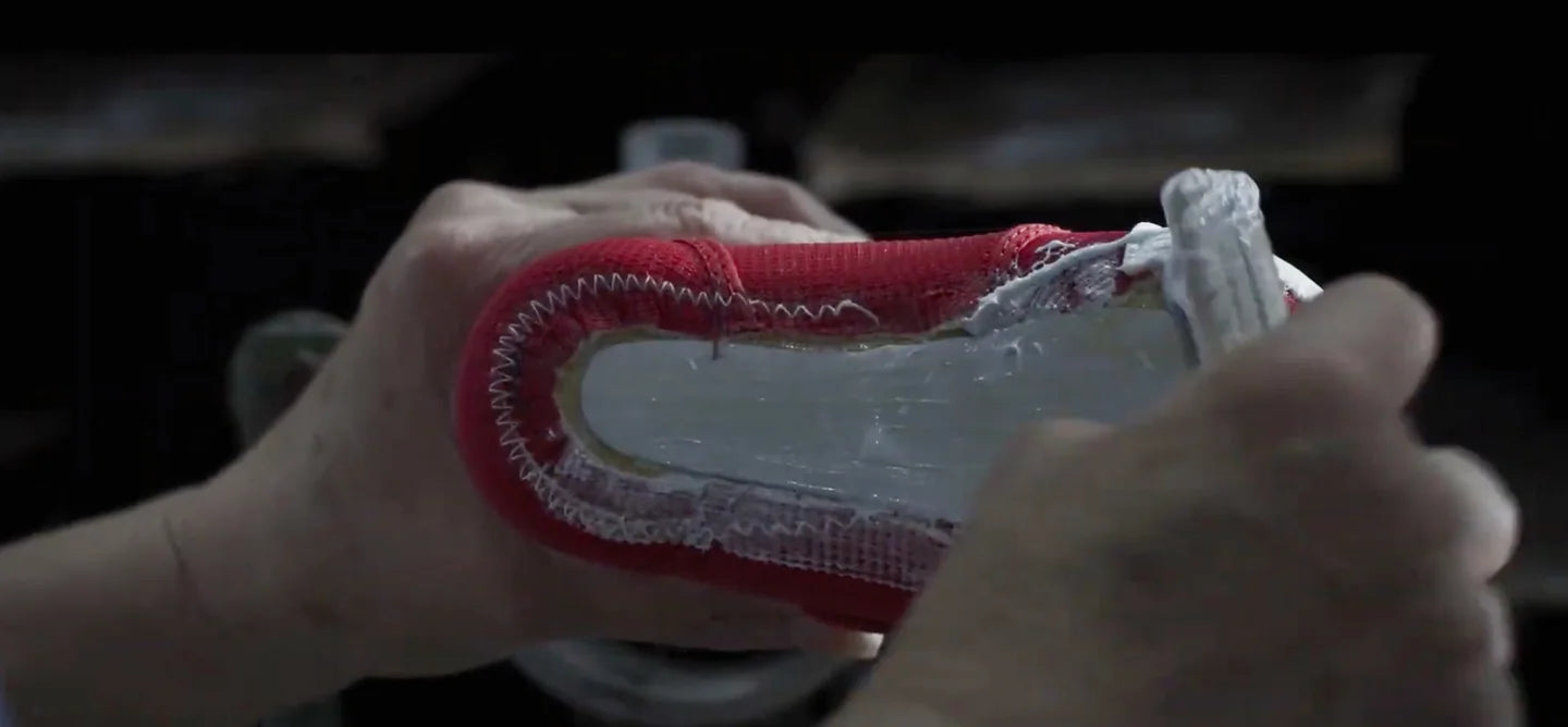 Hands carefully shape a small MIKI HOUSE shoe around a shoe last