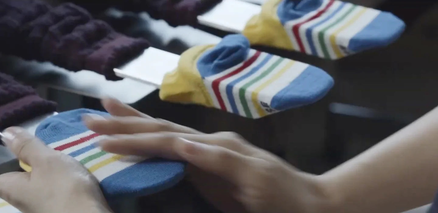 A craftsperson arranges colorful knitted MIKI HOUSE socks